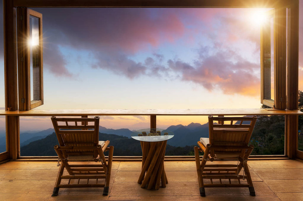 Krásná krajina v café styl minimální s dřevěnými stoly a židlemi terasou proti venkovní Mountain view v kavárně při východu slunce. - Fotografie, Obrázek