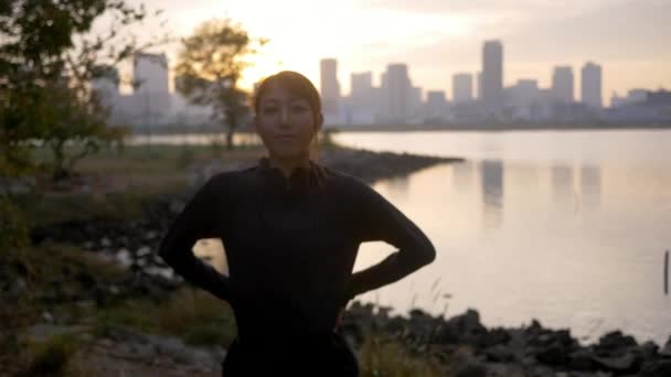 Beautiful healthy female runner stretching and breathing outside city sunrise - Imágenes, Vídeo
