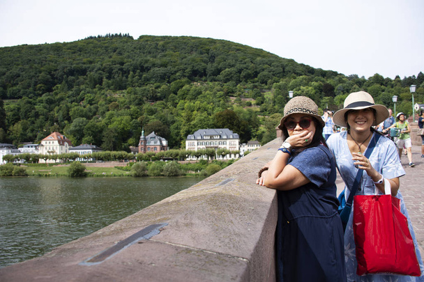 アジアのタイの女性の母親と娘の旅行とバーデン = ヴュルテンベルク州、ドイツのハイデルベルクまたは Heidelberger の旧市街でカール ・ テオドール ・旧橋の写真を撮るのためのポーズ - 写真・画像