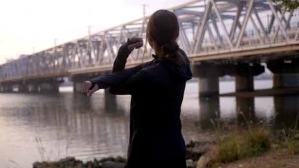 Young fitness woman stretching as train crosses bridge, HD, slow motion. - Video, Çekim