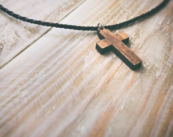 The cross-shaped pendant on the wooden desk - Fotoğraf, Görsel