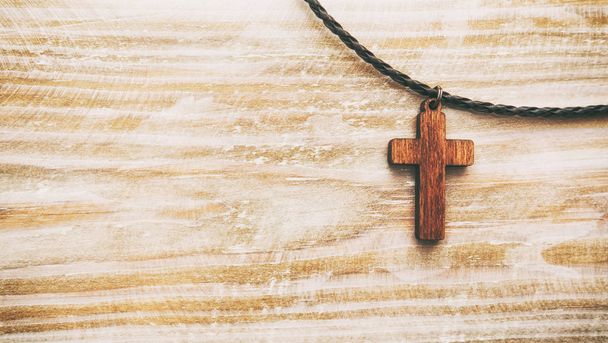 The cross-shaped pendant on the wooden desk - Фото, изображение