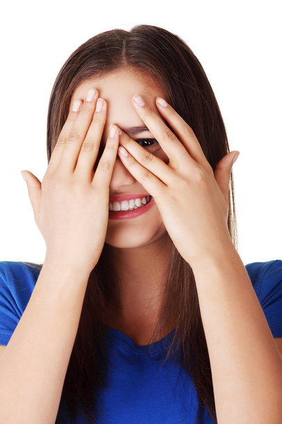Shy teenage girl peeking through covered face - Фото, изображение
