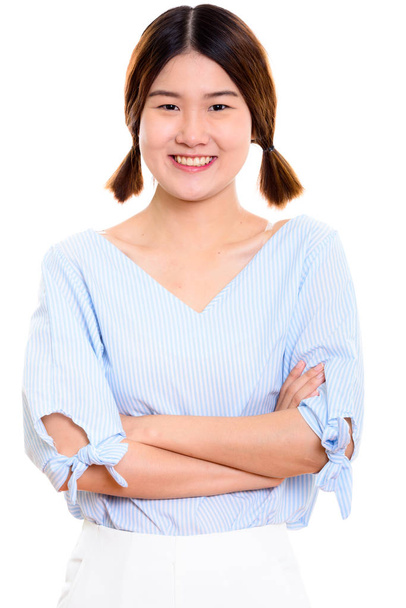 Студийный снимок молодой счастливой азиатки, улыбающейся со скрещенными руками - Фото, изображение