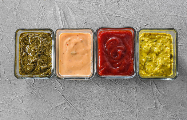 Різні смачні соуси в мисках на сірому фоні
 - Фото, зображення
