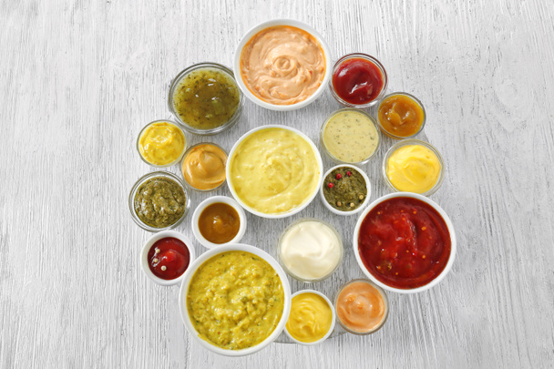 Different tasty sauces in bowls on white wooden table - Photo, Image