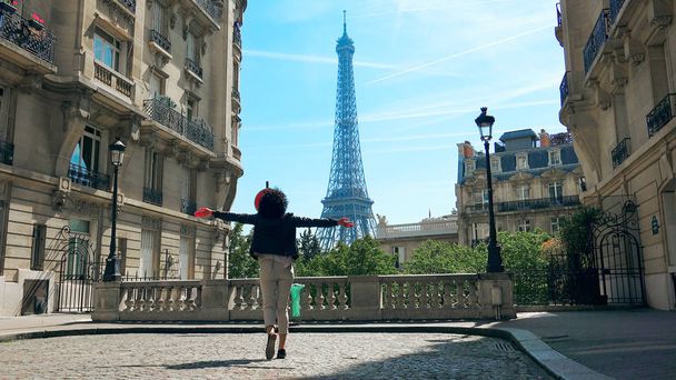 Young stylish happy woman walking the Camoens Avenue street rising hands and turning with eiffel tower on the background in Paris - Photo, image