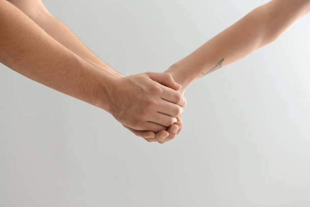 Άνθρωπος που κρατά το χέρι της γυναίκας σε ανοιχτόχρωμο φόντο - Φωτογραφία, εικόνα