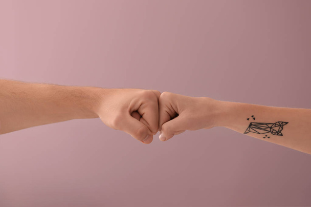 Mann und Frau machen Faustschlag-Geste auf farbigem Hintergrund - Foto, Bild