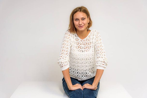 Portrait of a young beautiful girl on a white background. She is in front of the camera in different poses with different emotions. - Foto, afbeelding