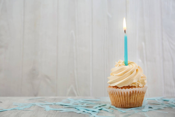 Delicioso cupcake de cumpleaños con vela encendida en la mesa
 - Foto, imagen
