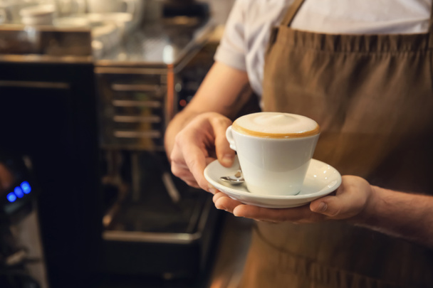 Бариста с чашкой свежего ароматного кофе в кафе
 - Фото, изображение