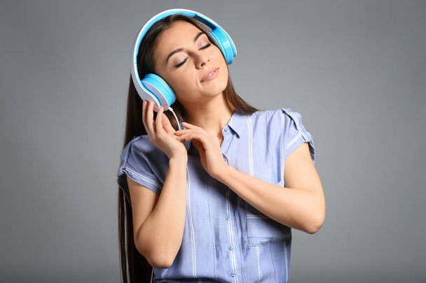 Όμορφη γυναίκα να ακούτε μουσική σε γκρίζο φόντο - Φωτογραφία, εικόνα