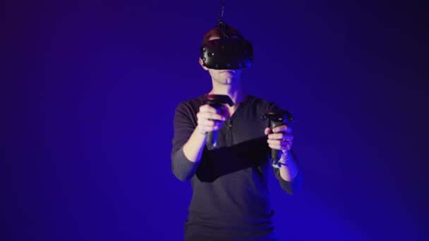 Young man using modern virtual reality headset with gamepad - Video