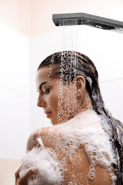 Красива молода жінка приймає душ у ванній
 - Фото, зображення