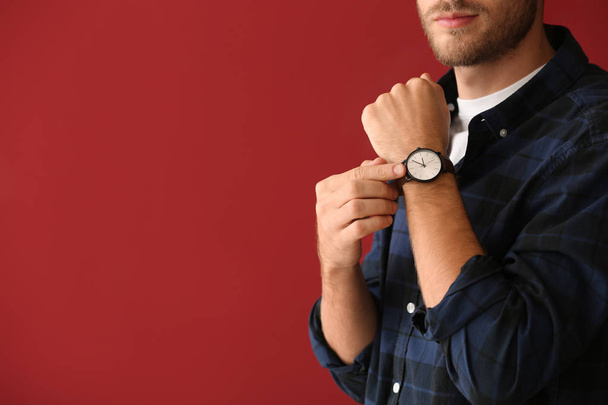 Young man with watch on color background - Photo, Image