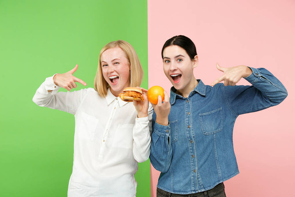 Diet. Dieting concept. Healthy Food. Beautiful Young Women choosing between fruits and unhelathy fast food - Fotó, kép