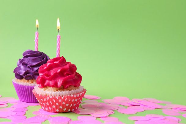leckere Cupcakes mit brennenden Kerzen auf farbigem Hintergrund - Foto, Bild