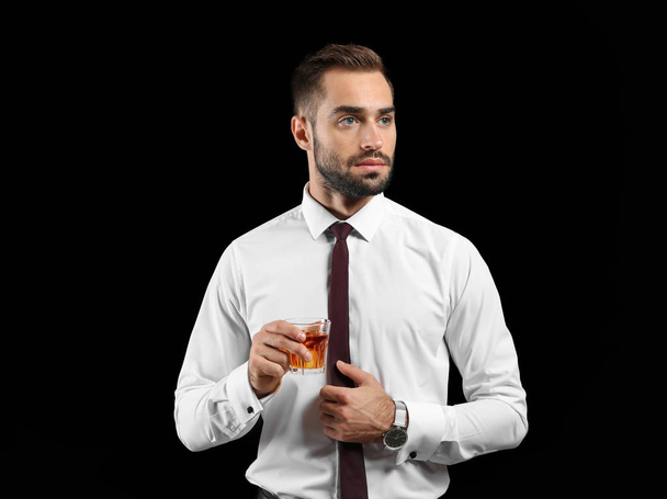Geschäftsmann mit einem Glas Whisky auf dunklem Hintergrund - Foto, Bild