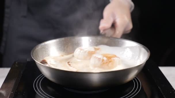 Cooking in restaurant professional cooker in gloves stiring frying pan with scallops boiling in cream sauce. Slow motion. hd - Footage, Video