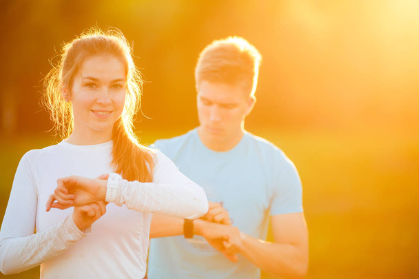 Image of pair young athletes looking at clock in park - Zdjęcie, obraz