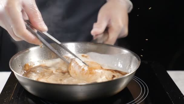 Chef-kok koken. Fornuis in handschoenen bereidt zeevruchten. Kokend van Sint-jakobsschelpen in roomsaus in koekenpan. HD - Video