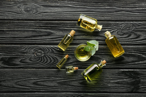 Botellas y tazón con aceite esencial de eucalipto sobre mesa de madera
 - Foto, imagen