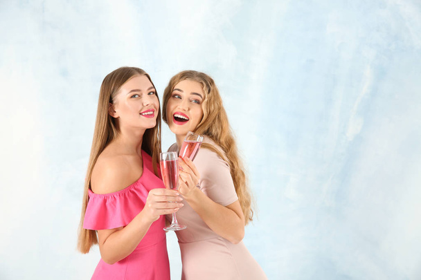Hermosas mujeres jóvenes con copas de champán sobre fondo claro
 - Foto, Imagen