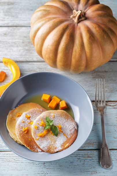 Hot tasty pancakes with pumpkin and honey in bowl on wooden table - Φωτογραφία, εικόνα