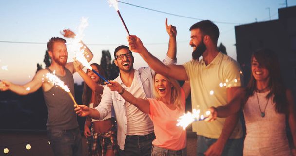 Group of friends enjoying rooftop party with sparklers - Foto, immagini