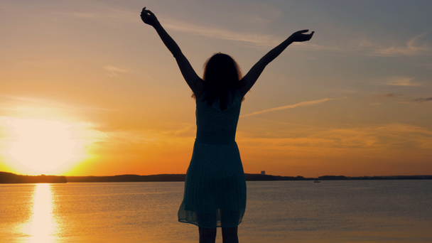Silhouette Of A Woman Facing The Sun Raises Her Hands Up At Sunset - Footage, Video