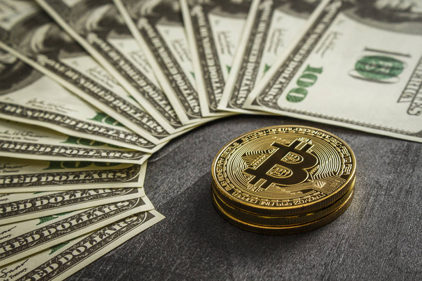 Coins in the form of bitcoin on a dark wooden table near the dollars - Valokuva, kuva