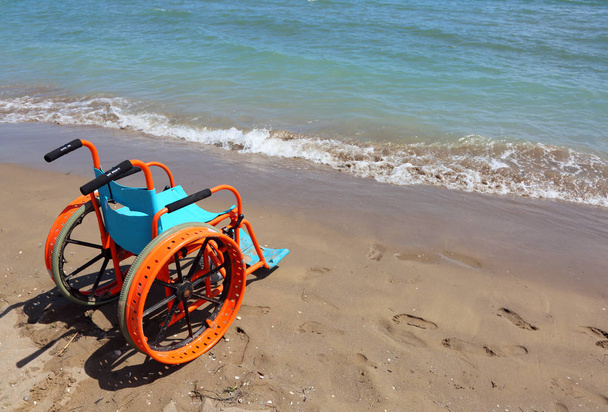 special wheelchair to the beach is placed near the blue sea - Photo, Image
