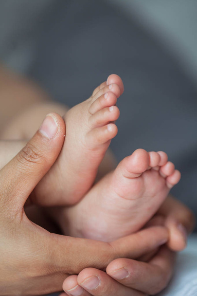 生まれたばかりの赤ちゃんの足のクローズ アップ。母の手で赤ちゃんの足。赤ちゃん。居心地の良い。家族. - 写真・画像