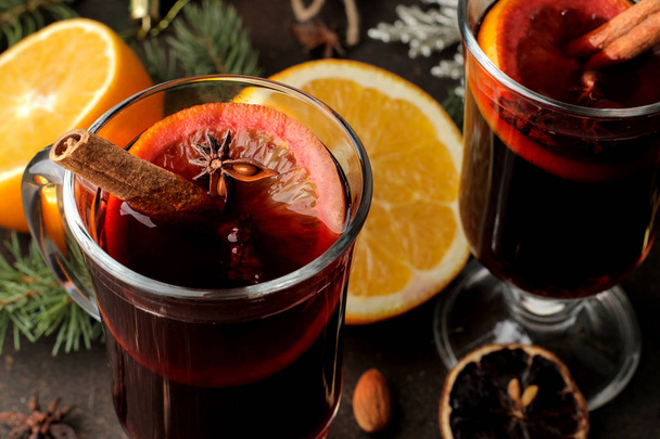 Hot mulled wine with cinnamon and orange in glass cups close-up and Christmas decorations on a dark background. Christmas. new Year. - Photo, Image
