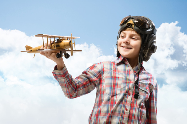 Niño en casco piloto jugando con un avión de juguete
 - Foto, Imagen