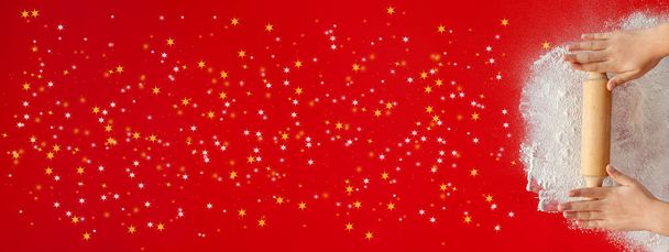 Μικρά χέρια με πλάστη και χριστουγεννιάτικα αστέρια πασπαλίστε κόκκινο τραπέζι - ζωηρό κόκκινο φόντο χώρο μεγάλο αντίγραφο, οριζόντια ή κάθετη μορφή banner Χριστούγεννα - Φωτογραφία, εικόνα