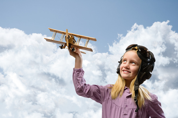 Mädchen im Helmpiloten spielt mit einem Spielzeugflugzeug - Foto, Bild