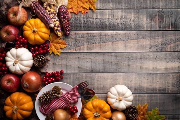 Bovenaanzicht van Autumn maple laat met pompoen, appel, maïs en rode bessen op oude houten achtergrond. Thanksgiving day concept. - Foto, afbeelding