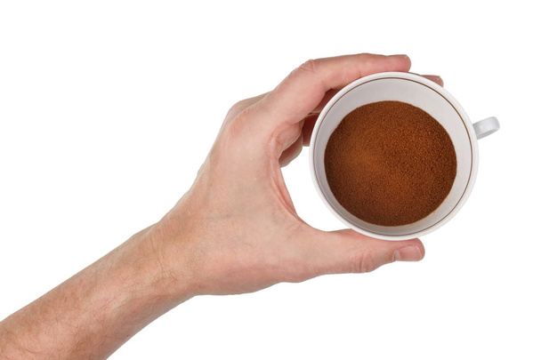 Un anciano sostiene en su mano una taza de porcelana llena de gránulos de café instantáneos. Aislado en blanco primer plano del estudio de tiro
 - Foto, Imagen