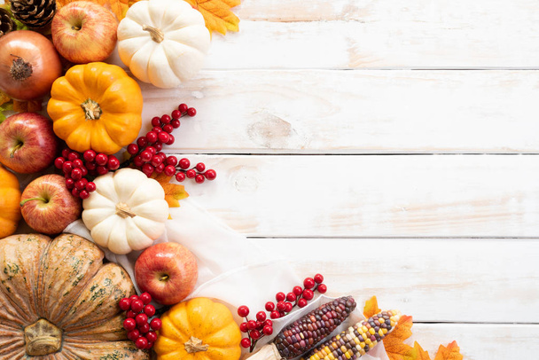 Ansicht von Herbst-Ahornblättern mit Kürbis und roten Beeren auf weißem Holzhintergrund. Konzept zum Erntedankfest. - Foto, Bild