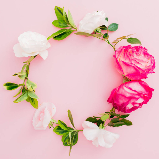 Cornice floreale con fiori di rose bianche e rosse e foglie su sfondo rosa. Posa piatta, vista dall'alto
. - Foto, immagini