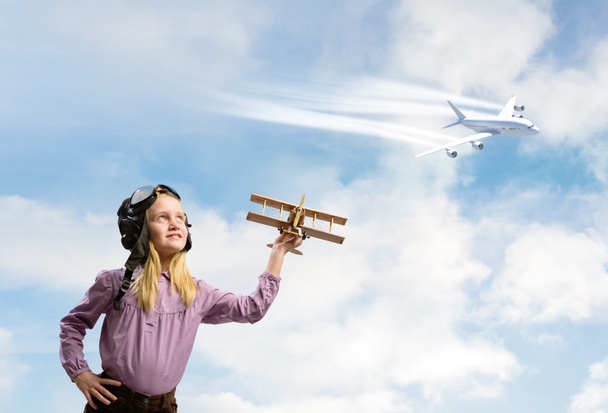 girl in helmet pilot playing with a toy airplane - Foto, Imagen