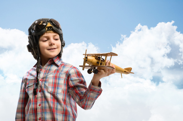 Boy in helmet pilot playing with a toy airplane - Foto, afbeelding