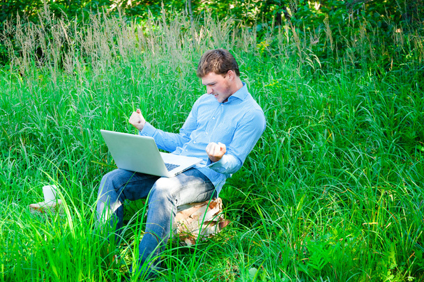 Young man outdoors with a cup and laptop - Фото, изображение