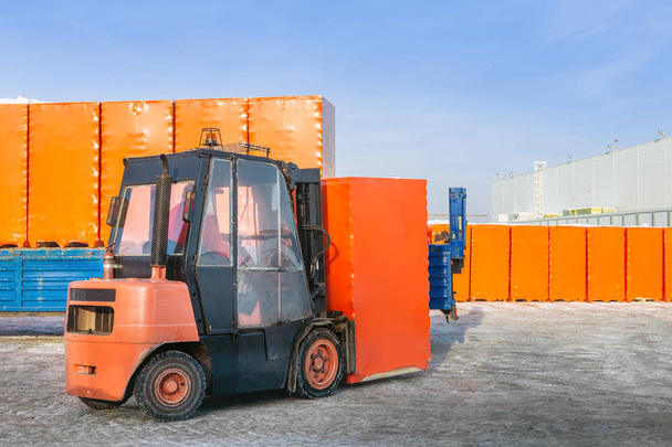 Vorkheftruck lossen vrachtwagen opleggers met verpakt kartonnen dozen buitenshuis. openair magazijn werkt achtergrond. - Foto, afbeelding