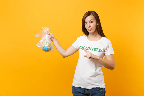 Жіночий портрет у білій футболці написаний напис "Зелений титул добровольця" тримається в поліетиленовій сумці Земляний світ глобус ізольований на жовтому тлі. Добровільна безкоштовна допомога, концепція благодійності
 - Фото, зображення