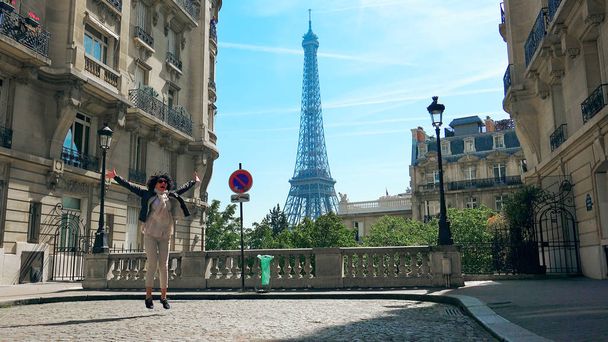 Young stylish happy woman walking the Camoens Avenue street rising hands and turning with eiffel tower on the background in Paris - Photo, image