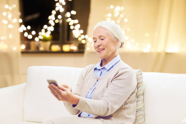 senior woman with smartphone at home on christmas - Foto, afbeelding