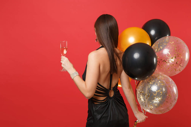 後ろの黒いドレスを祝って、若い女性観は赤の背景に分離気球、シャンペンのガラスを保持しています。聖バレンタインの日新年あけまして誕生日モックアップ休日党概念 - 写真・画像